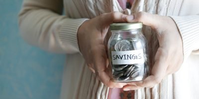 a woman holding a jar with savings written on it